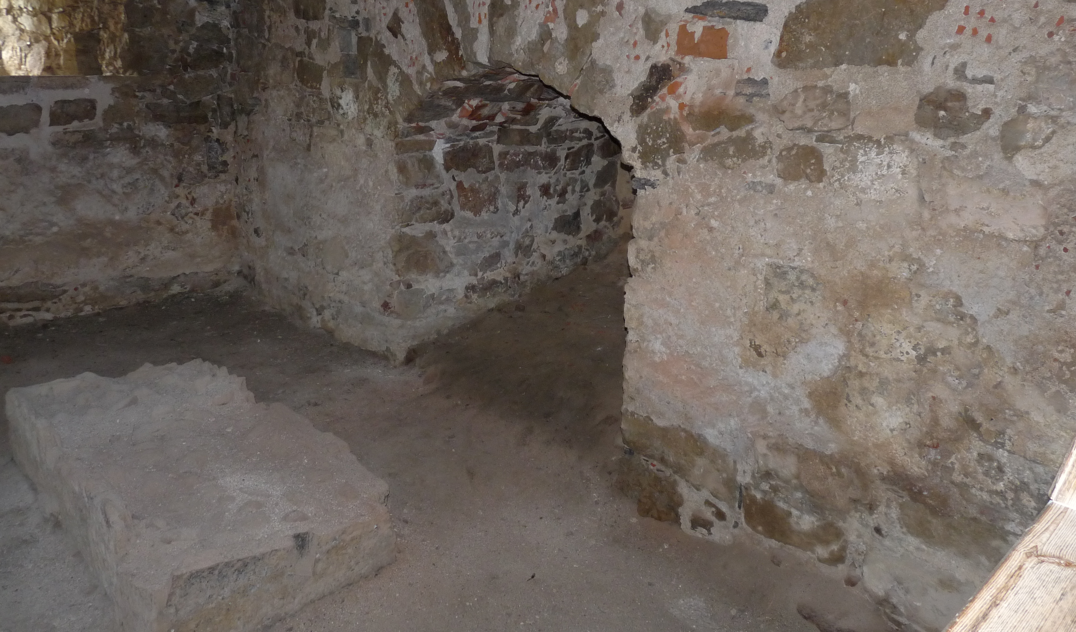 The picture shows part of the kitchen with a hearthstone on the left and a wall opening in the middle for heating the hypocaust.