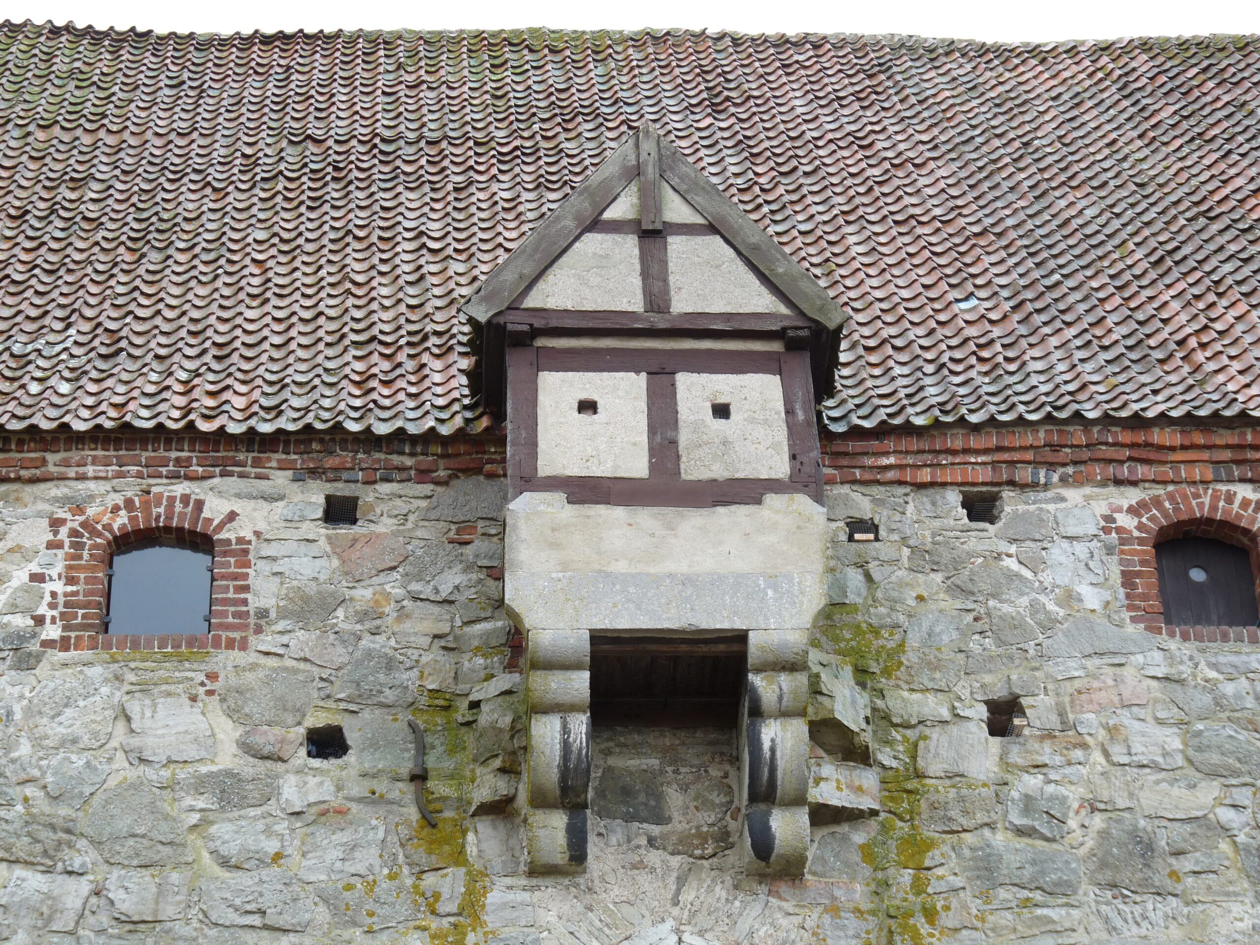 A projecting extension high up on the castle's outer wall, just below the roof.