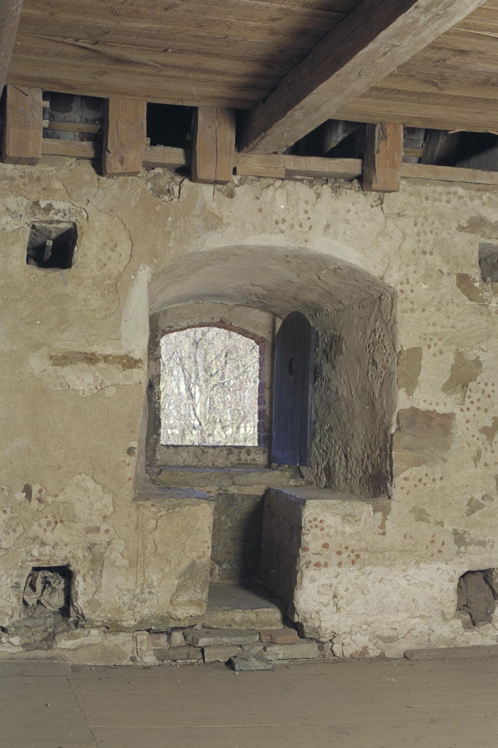 Bilden visar en fönsternisch med två sittplatser av sten. Ovanför ses del av takstolens bjälkar.