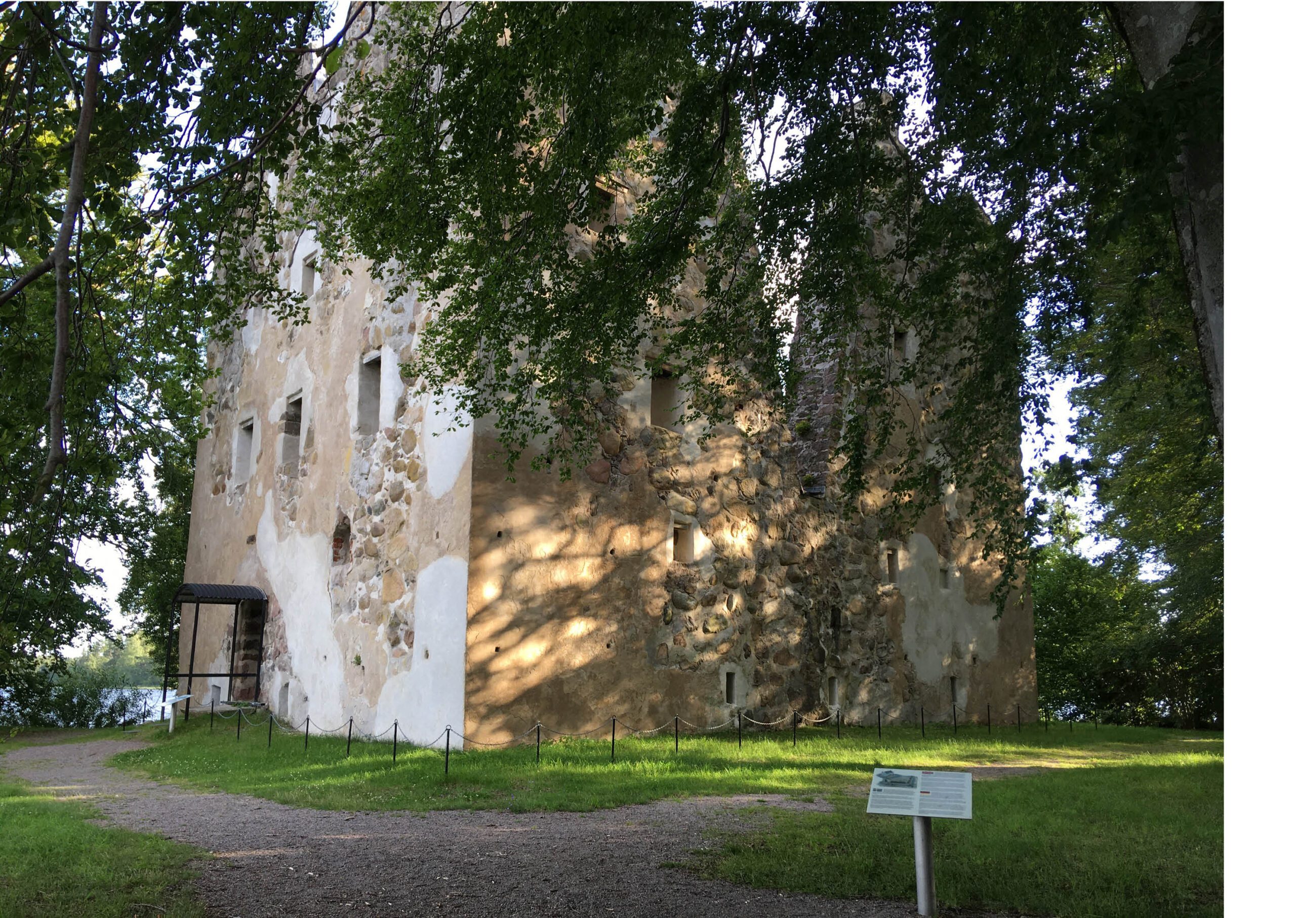 Bilden visar Bergkvara slottsruin med lövträd i förgrunden.