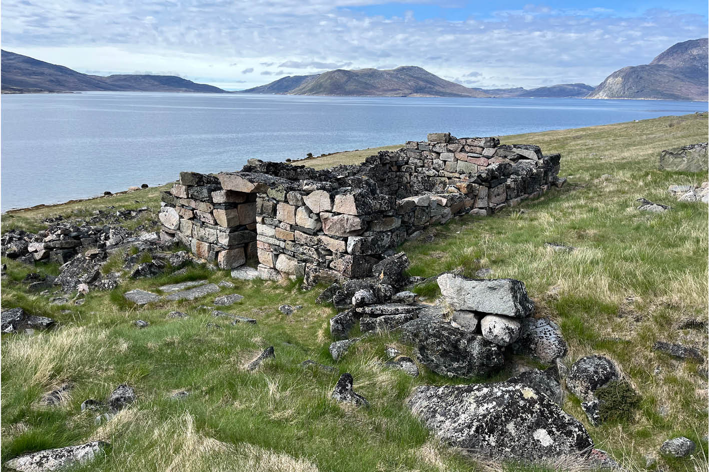 Ruin av en medeltida hallbyggnad av sten vid en grönländsk fjord.