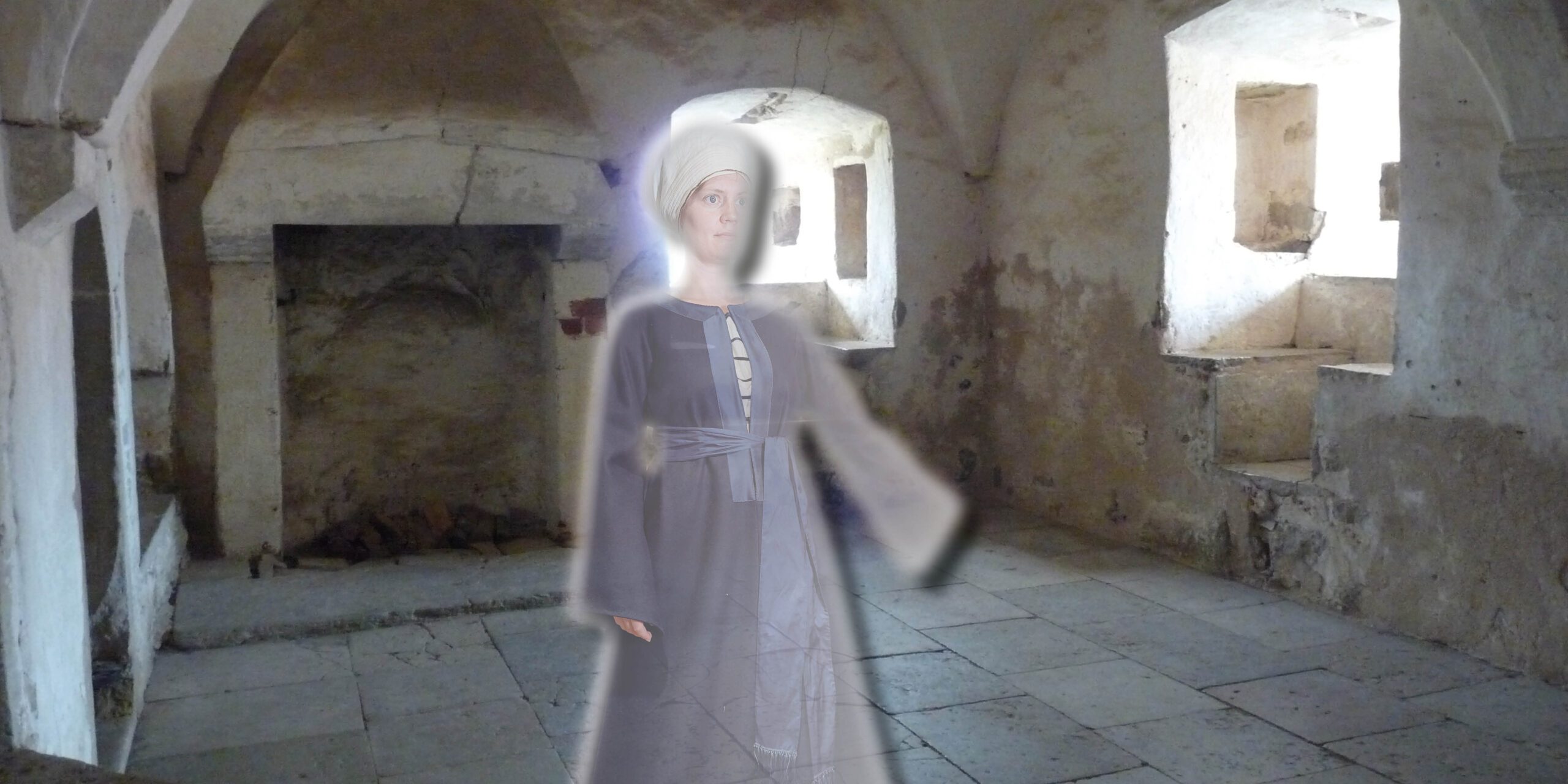 Ett kvinnligt spöke i medeltidskläder står i ett av rummen i borgen.