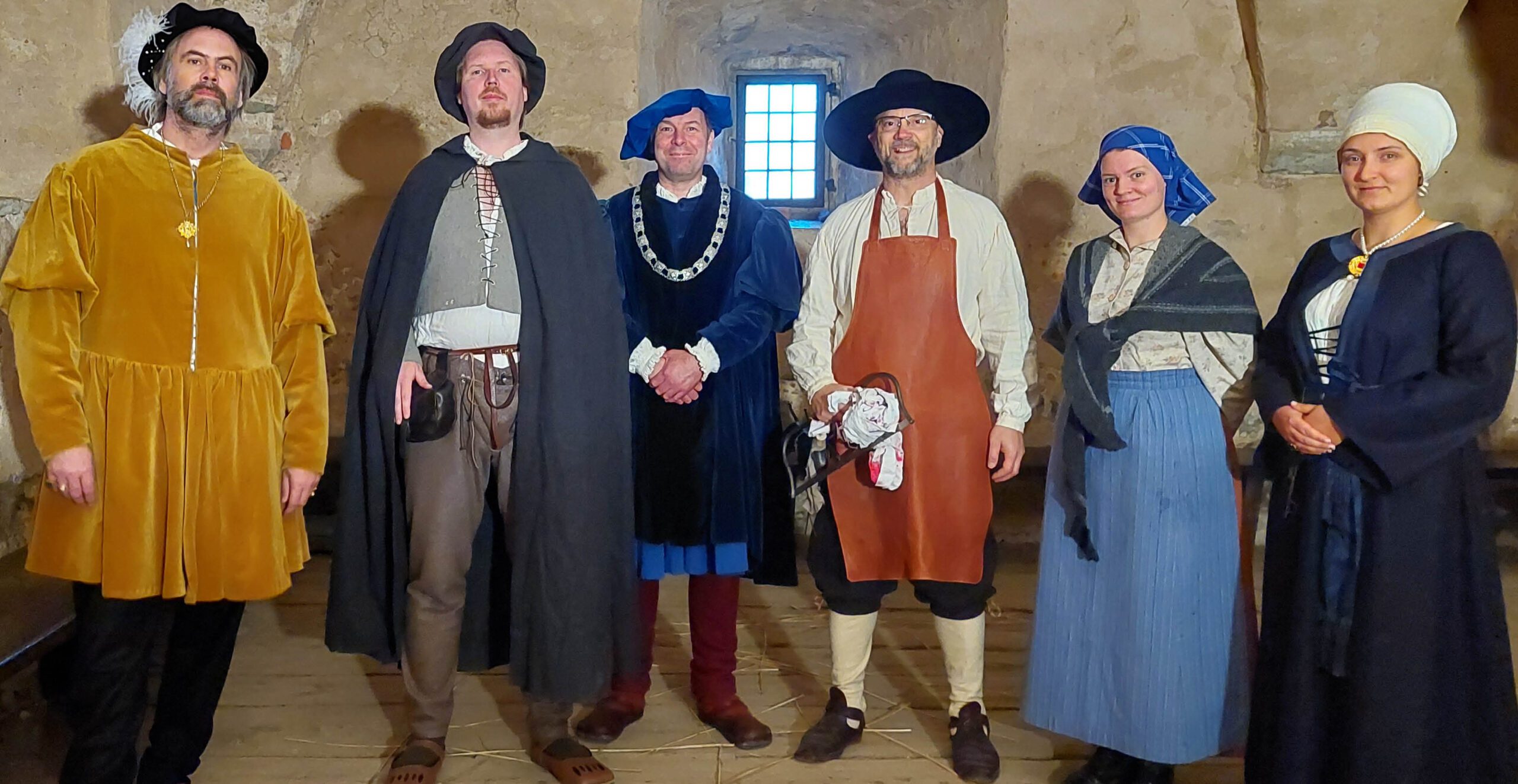 Bilden visar personer i historiska kläder i borgen.