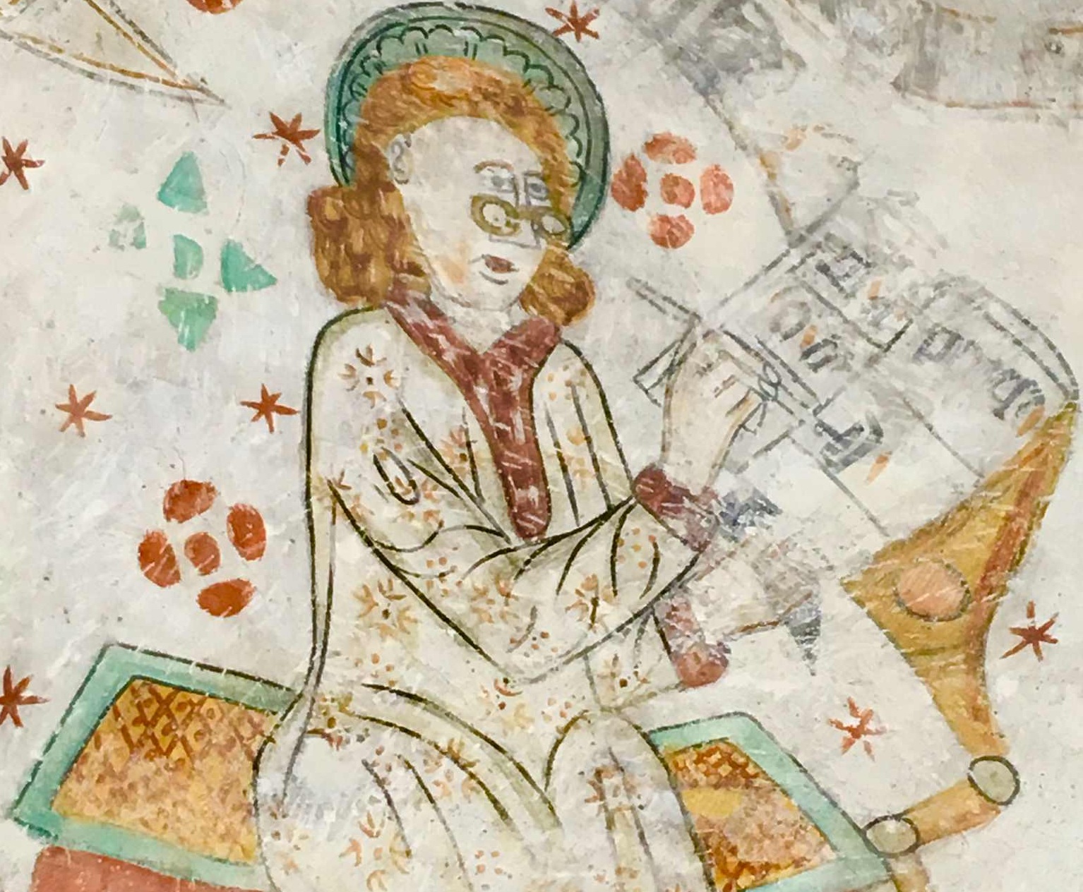 En medeltida skrivare med glasögon skriver vid sin pulpet.