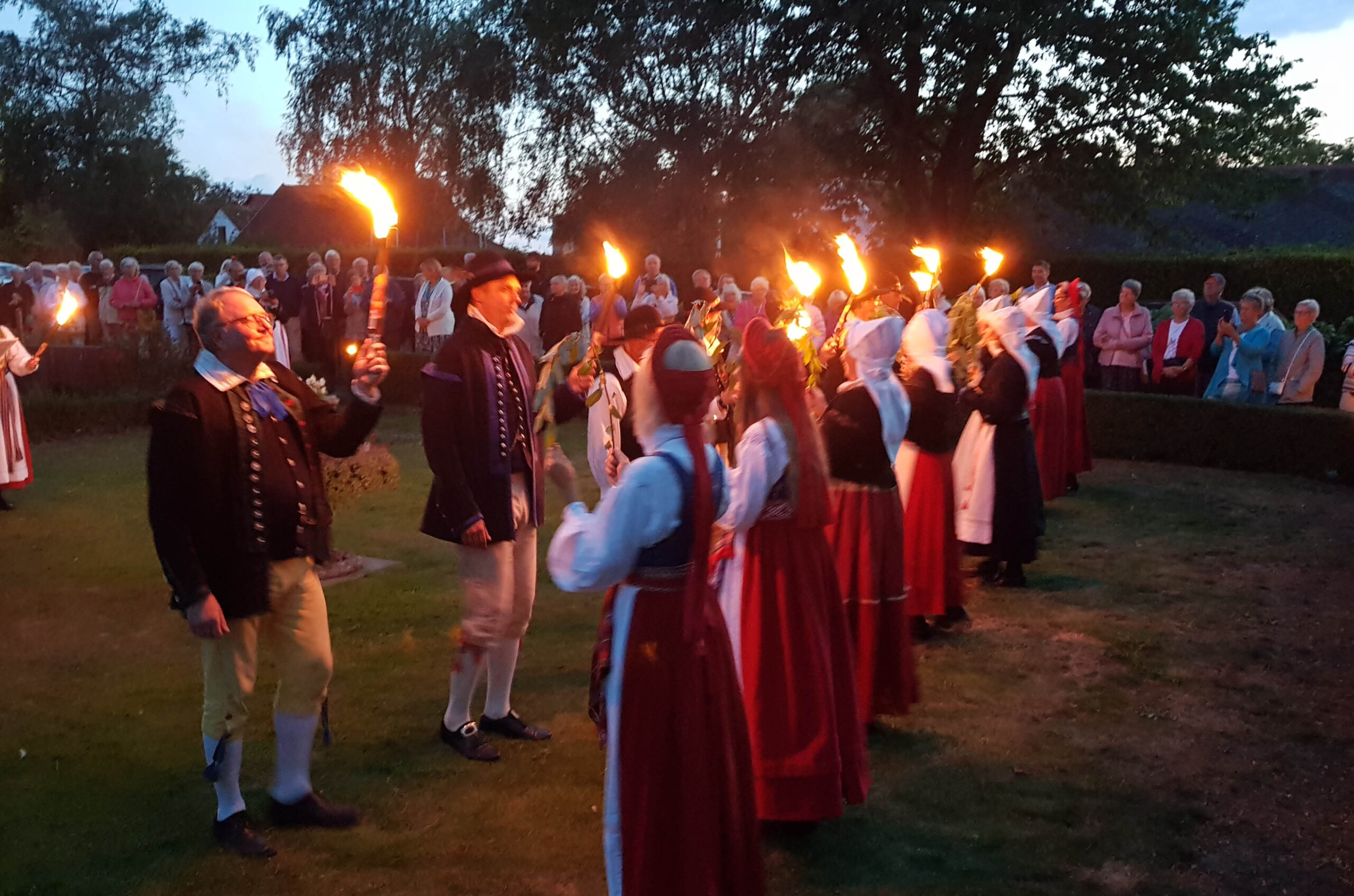 A group of folk dancers with torches.